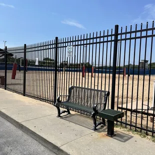 a bench on a sidewalk next to a fence