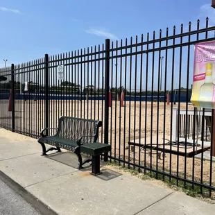 a bench on a sidewalk next to a fence