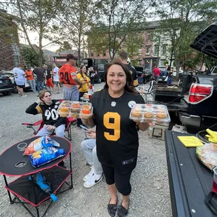a woman holding a tray of sandwiches
