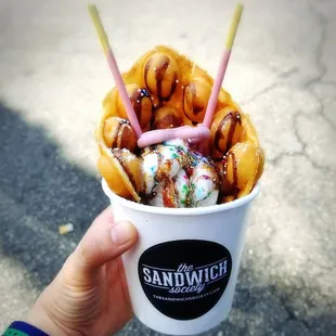 a hand holding a cup of ice cream