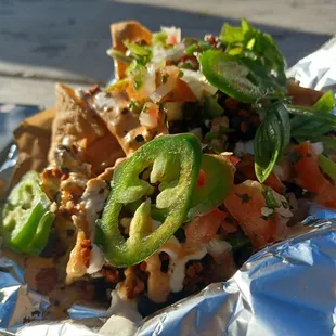 Loaded veggie nachos with soyrizo, black beans, cheeze sauce, pico, green onions and jalapeños on top.