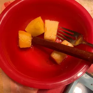 a red bowl of fruit with a fork in it