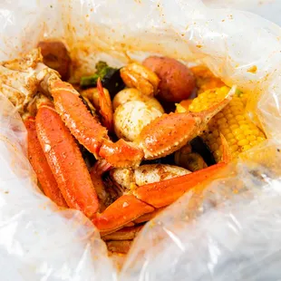 crab legs, corn and potatoes in a plastic bag