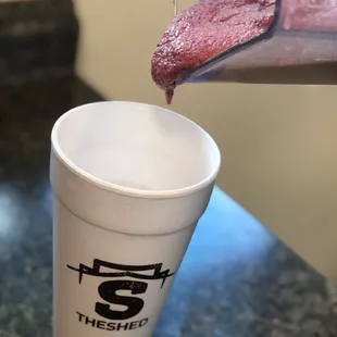 a cup of liquid being poured into a blender