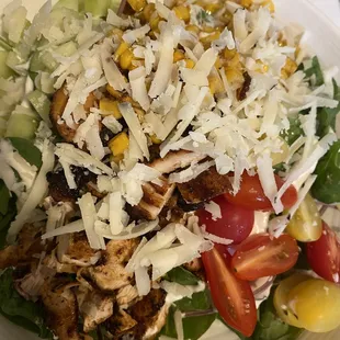 a salad with chicken, lettuce, tomatoes, corn and cheese