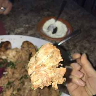 a person holding a piece of fried chicken