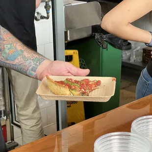  a man handing a slice of pizza to a woman