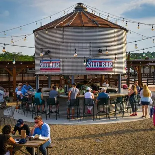 a group of people sitting at tables in front of a silo