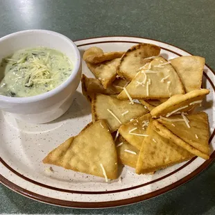 An appetizer of spinach artichoke dip and pita bread