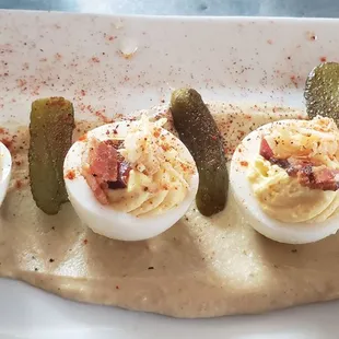 Deviled eggs topped with crab meat and bacon on top of hummus