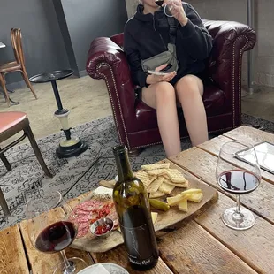a woman sitting on a couch with a glass of wine and a plate of food