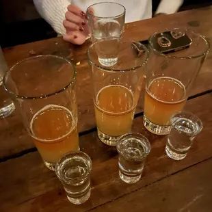 a woman sitting at a table with glasses of beer