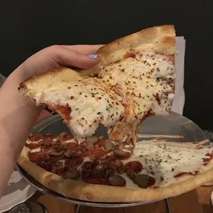 a person taking a slice of pizza