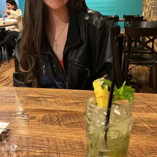 a woman sitting at a table with a drink