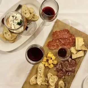 a plate of meat, cheese, crackers, and wine