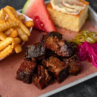 a plate of ribs, fries, watermelon, and a slice of watermelon