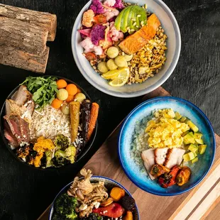 three bowls of food on a cutting board
