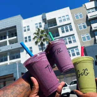 a hand holding two cups of smoothie