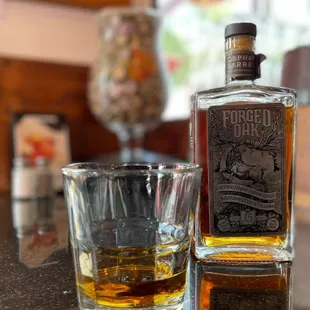 a glass of whiskey and a bottle of bourbon