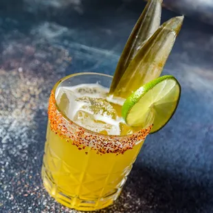 a cocktail with a pickle garnish
