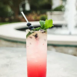 a glass of a drink with a mint leaf garnish