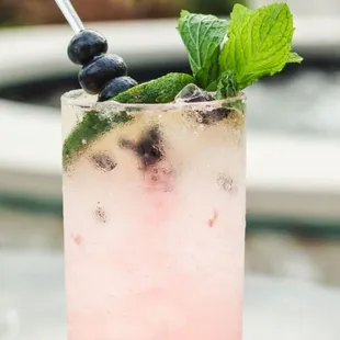 a pink cocktail with mint and blueberries
