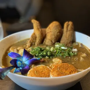 a bowl of soup with a purple flower