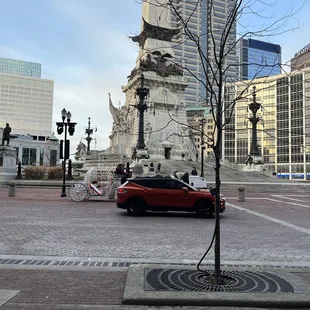 a red car parked in front of a clock tower