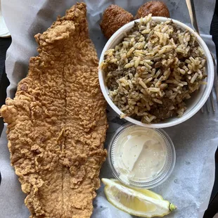 fried fish and rice with a side of lemon wedges