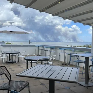 tables and chairs on a patio overlooking the ocean