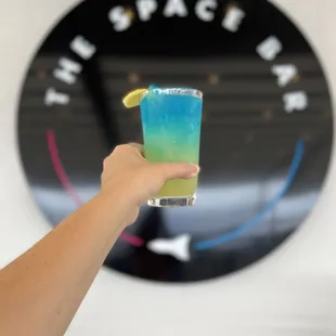 a hand holding a blue and green drink