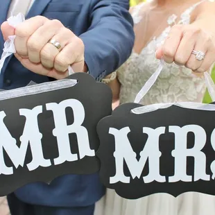 a bride and groom holding mr and mrs signs