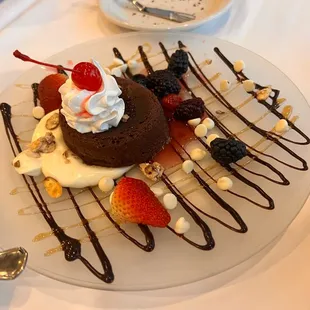 a chocolate cake with whipped cream, strawberries, and cherries