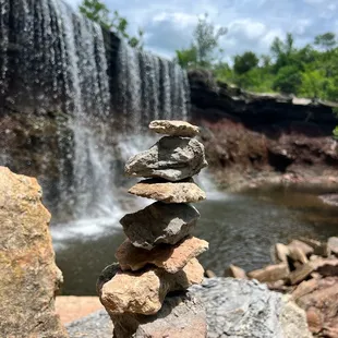 stacked rocks in front of a waterfall