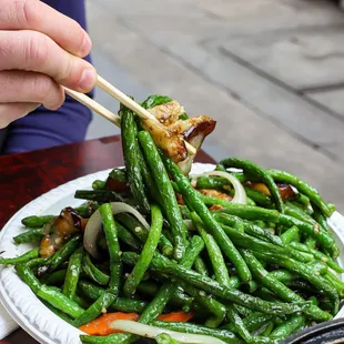 a plate of green beans with chopsticks