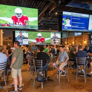  a large group of people sitting at tables watching tvs