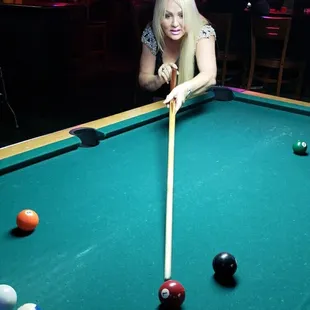 a woman leaning over a pool table