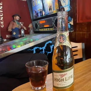 a bottle of high life next to a glass of liquor