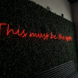 A nice neon sign and faux garden wall greets you at the front door.