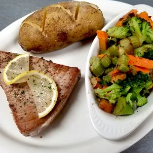 a plate of food with meat, vegetables and a baked potato