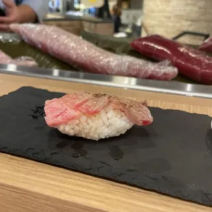 a piece of sushi on a black plate
