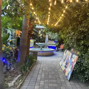 an outdoor stage with a fountain and string lights