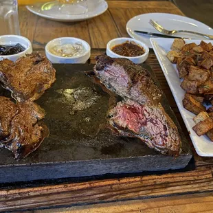 a steak and potatoes on a stone plate