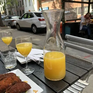 a table with a pitcher of orange juice and two glasses of orange juice
