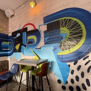 a table and chairs in front of a graffiti wall