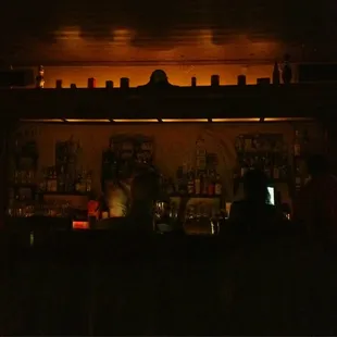 a dimly lit bar with people sitting at the bar