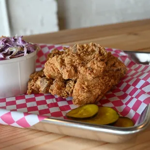 a tray of fried chicken with a side of coleslaw