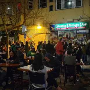 people sitting at tables outside a restaurant