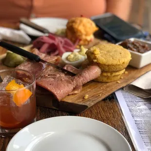 a platter of meats, breads, and drinks