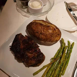 Half of a ribeye with asparagus  baked potato w/toppings